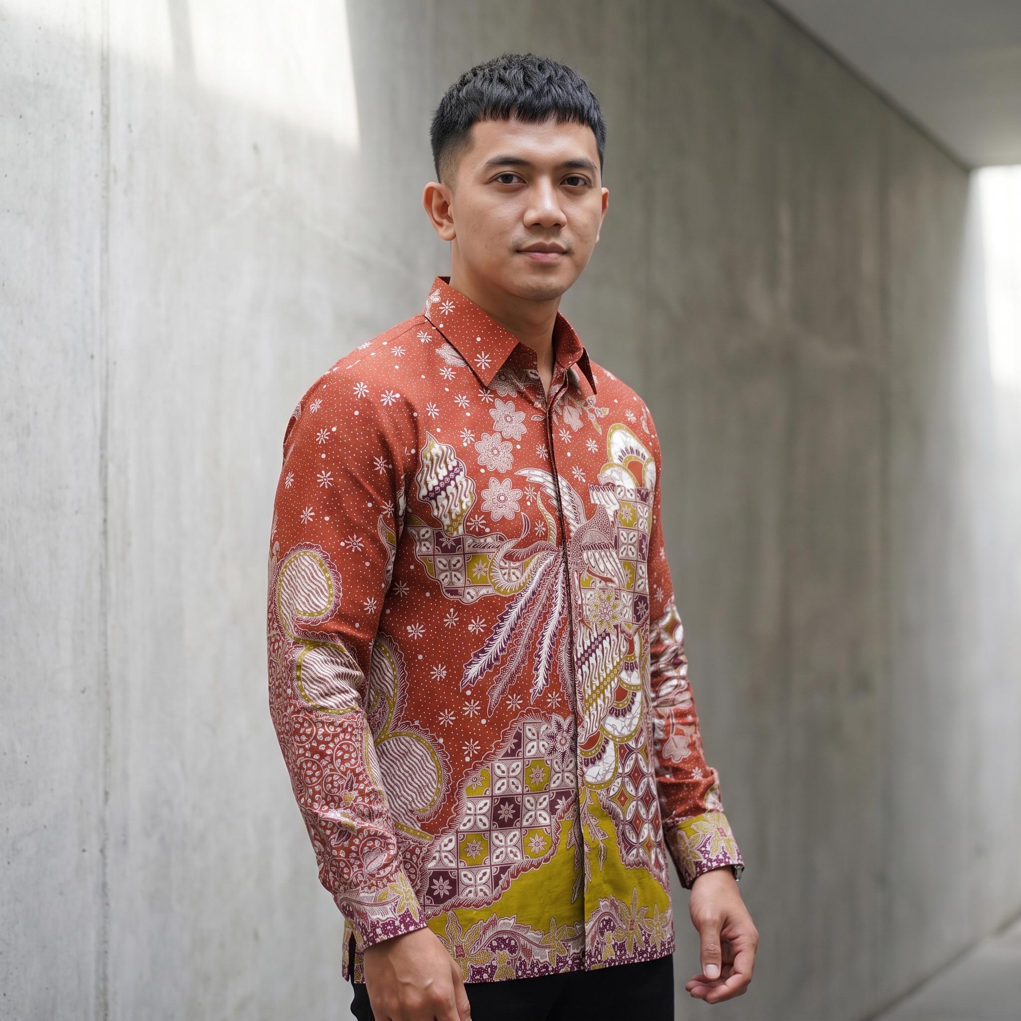 Kemeja batik pria lengan panjang katun premium warna merah bata motif garuda dengan jahitan clean look.